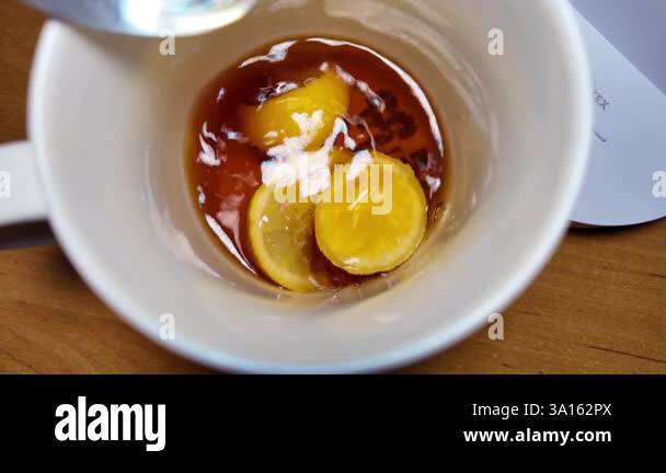 black tea and lemon slow motion video. tea in a cup. lemon floating in ...