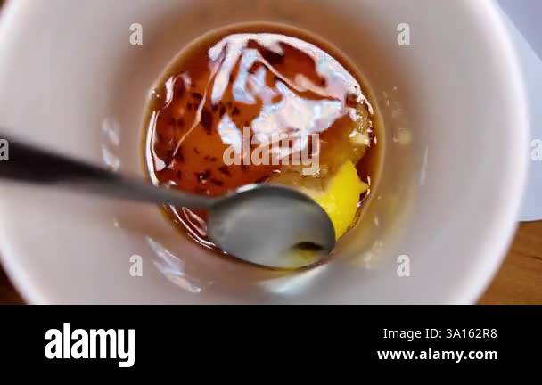 black tea and lemon slow motion video. tea in a cup. lemon floating in ...