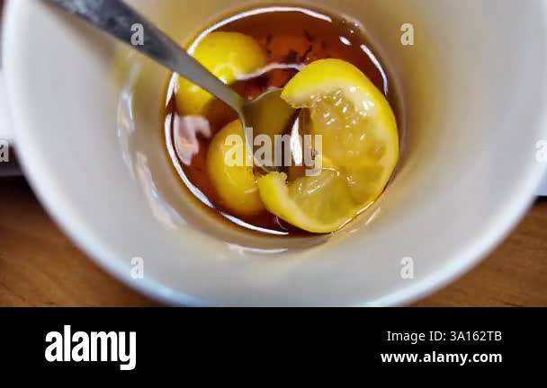 black tea and lemon slow motion video. tea in a cup. lemon floating in ...