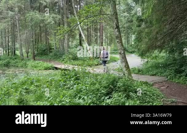 A woman goes hiking across the river along a pedestrian bridge. High ...