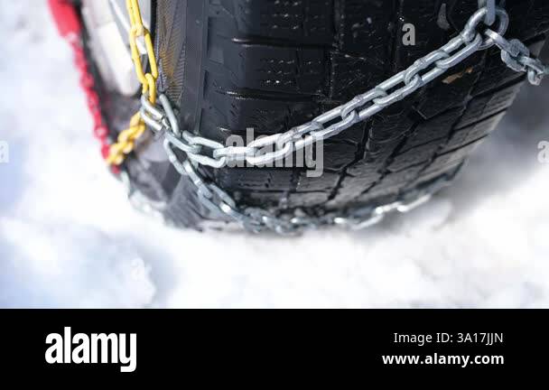 Close-up of a winter tire with metal snow chains for better traction on ...