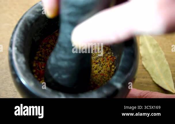 Hand Grinding Spices in black Stone Mortar. Grinding Aromatic Spices in ...