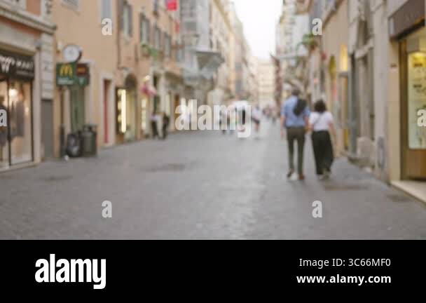 Out-of-focus street scene in rome featuring blurred pedestrians walking ...