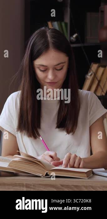Cheerful student is preparing her homework at home. Young smiling ...