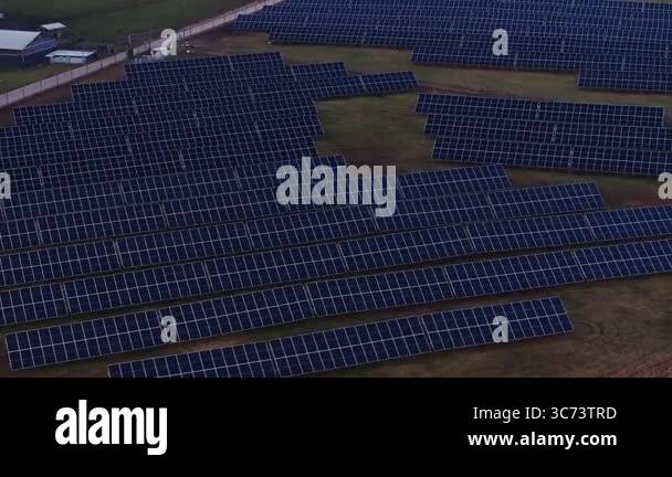 Solar Module Boundary Rows of solar panels arranged in a grid cover a grassy field, with ...