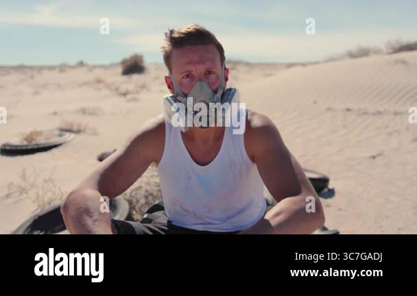 In a desolate desert, a man with a respirator mask conveys an ...
