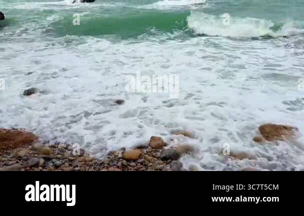 The ocean waves crash dramatically against a rugged and untamed ...