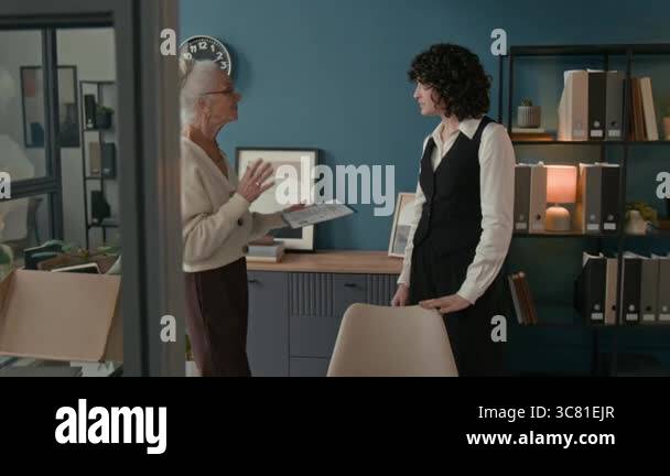 Medium shot of elderly woman briefing younger colleague taking her ...