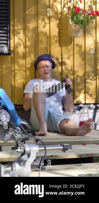 Middle-aged man enjoying a drink and relaxing barefoot while building a ...