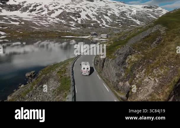 A beautiful RV travels along a winding road, surrounded by dramatic ...