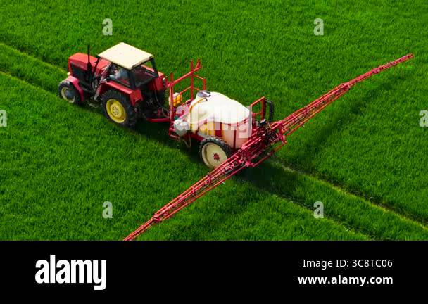 Farmer on tractor spraying wheat field. Operator driving machine ...
