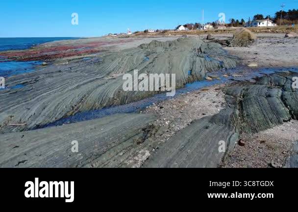 Quebec Rocks On Beach A geological formation of sedimentary rocks surfaces on a beach under a ...