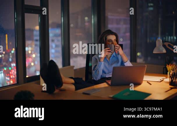 Calm manager enjoy coffee break at night company office with bright ...
