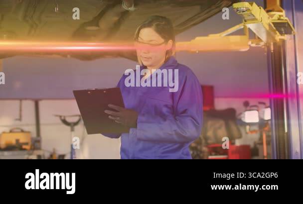 Female mechanic holding clipboard inspecting car chassis in auto repair ...