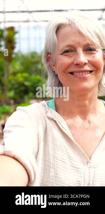 Senior woman capturing joyful moment while taking selfie among vibrant ...