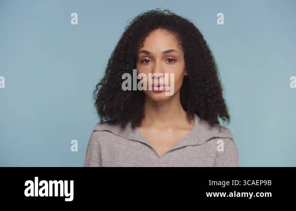 Portrait of a young woman with curly hair subtly shaking her head in ...