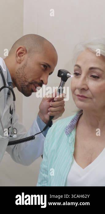 Medical professional performing ear examination on senior female ...