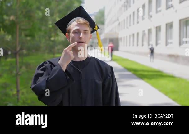 Caucasian young man in graduation gown communicating using sign ...