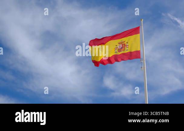 Spanish flag waving gracefully against a bright blue sky. A powerful ...