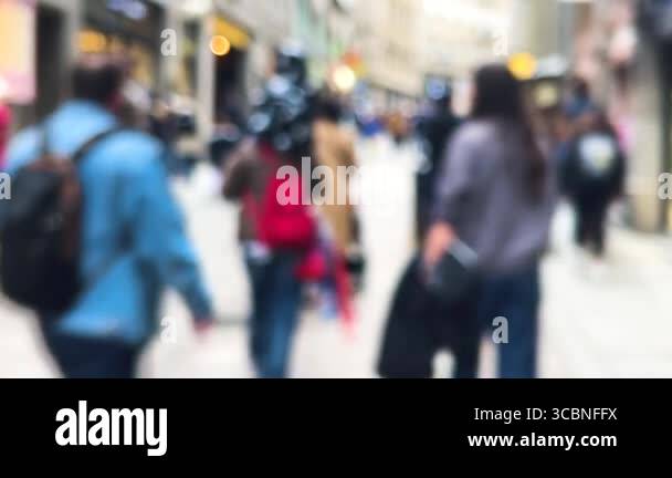 People walk along a busy street with shops and restaurants in an old ...