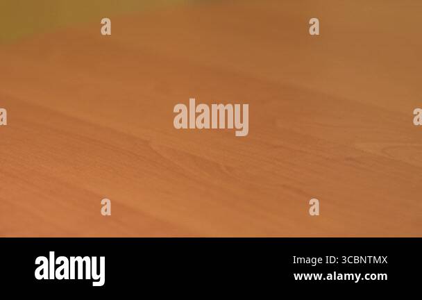 Wiping dust from a wooden table using a soft rag in a bright room. A ...