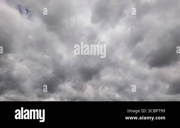 Timelapse of dramatic grey storm clouds moving fast across the sky ...