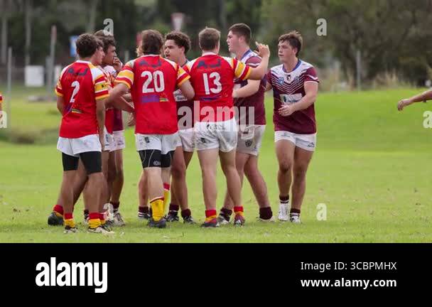 Teen rugby players engage in a heated exchange on a grassy field under ...