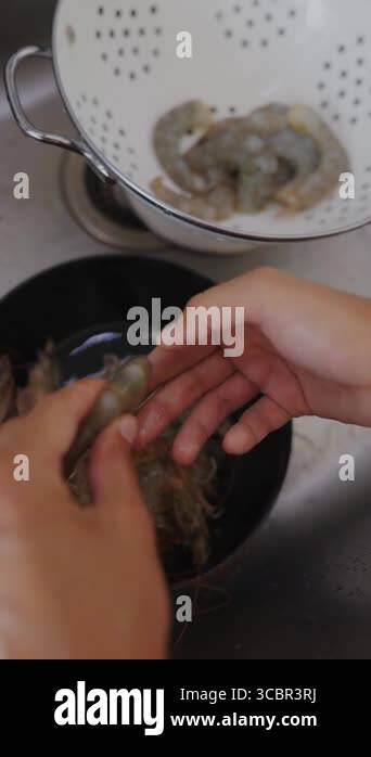 Hands diligently preparing shrimp in a bowl, skillfully showcasing the ...