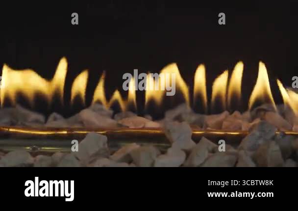 Yellow flames rise in a linear pattern from a gas fireplace with white ...
