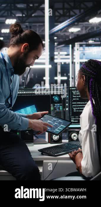 Vertical video System administrator and employee in data center coding ...
