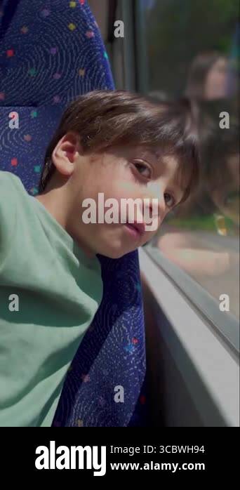 Boy leaning against bus window looking outside with thoughtful ...