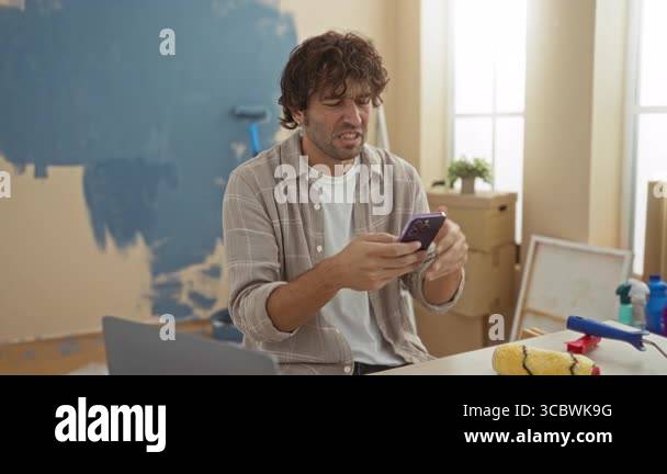 View of Young man frustrated in living room checking phone during home ...