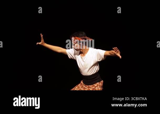 A young male dancer performing on stage, wearing a traditional outfit ...