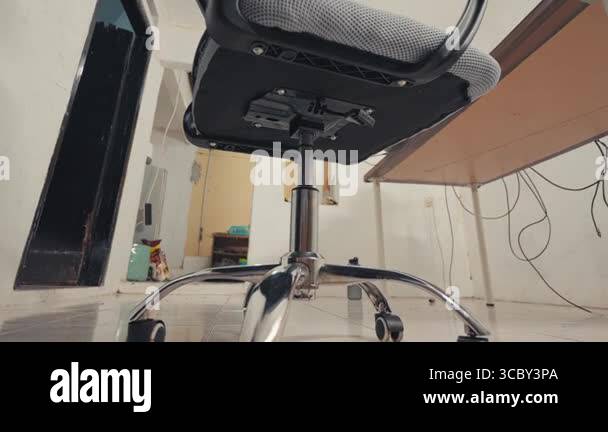 A low-angle view of an office chair, showcasing its base and wheels ...