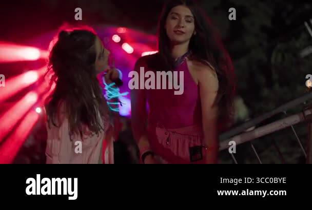 Two happy young girls dancing on open space party with flashing lights ...