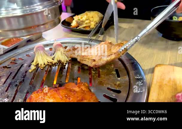 Close-up of Korean BBQ meat grilling on a tabletop grill in a Bangkok ...