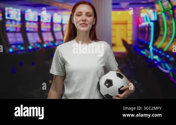 Woman holding soccer ball in casino with slot machines around and ...