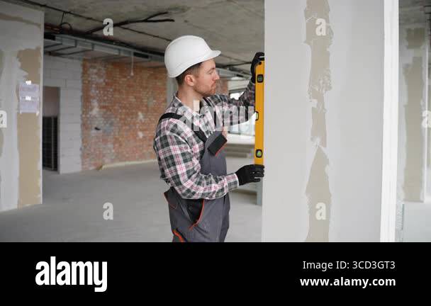 Professional builder using spirit level, meticulously checking wall ...