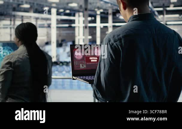 Engineer in server room receives critical error popup on laptop screen ...