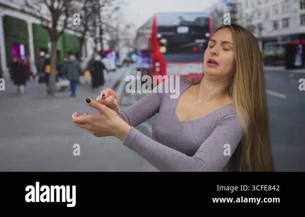 Woman pulling an imaginary rope on a busy city street with a red bus ...