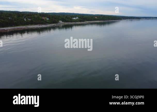 View of Panoramic aerial video of a peaceful coastline with a beach, houses ...