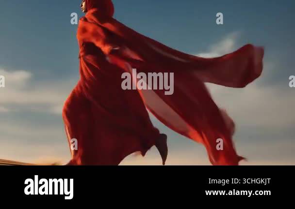 Graceful female running wrapped in flowing red fabric performs amidst a ...
