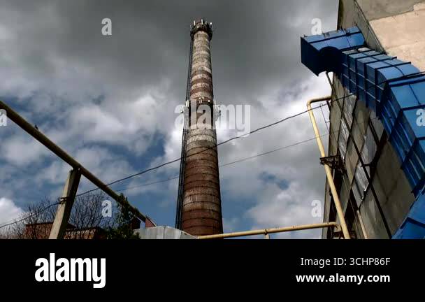 Tall industrial chimney against the background of cloudy gray sky with ...