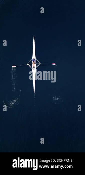 Drone aerial video of a single rowing athlete moving across calm deep ...
