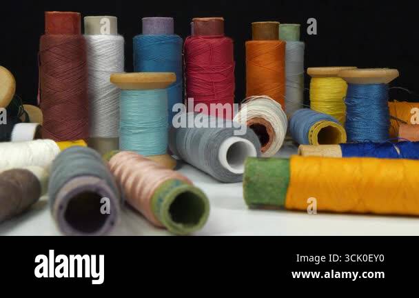 Coloured spools of thread lie on white table on black background Stock ...