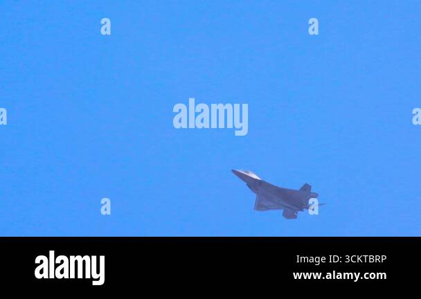 F-22 Raptor jet executes dynamic aerial maneuvers against a clear blue ...