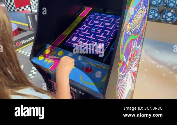 Pac Man Buttons. Machine Dubai, UAE, 9 june 2025. Child playing classic Ms. Pac-Man on arcade ...