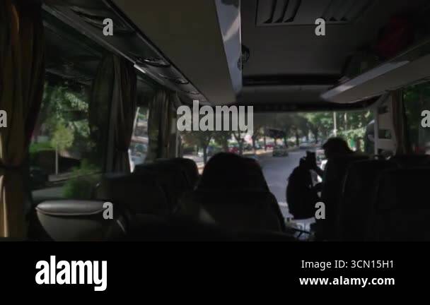 Passengers seated inside tour bus looking out window at city street ...