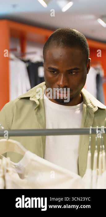 Man Browsing Racks African American male browsing clothing rack, selecting white t shirt ...