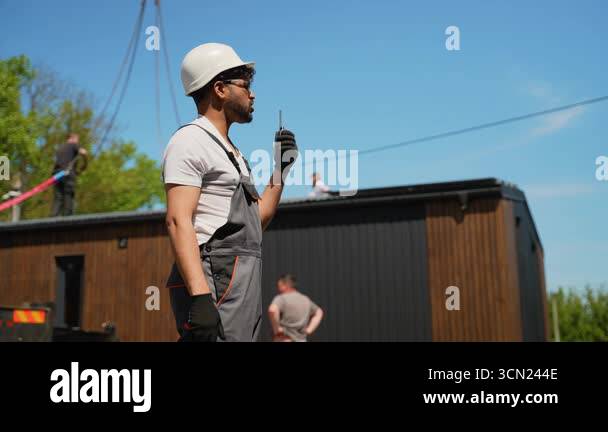 Construction worker wearing safety helmet and gloves using walkie ...